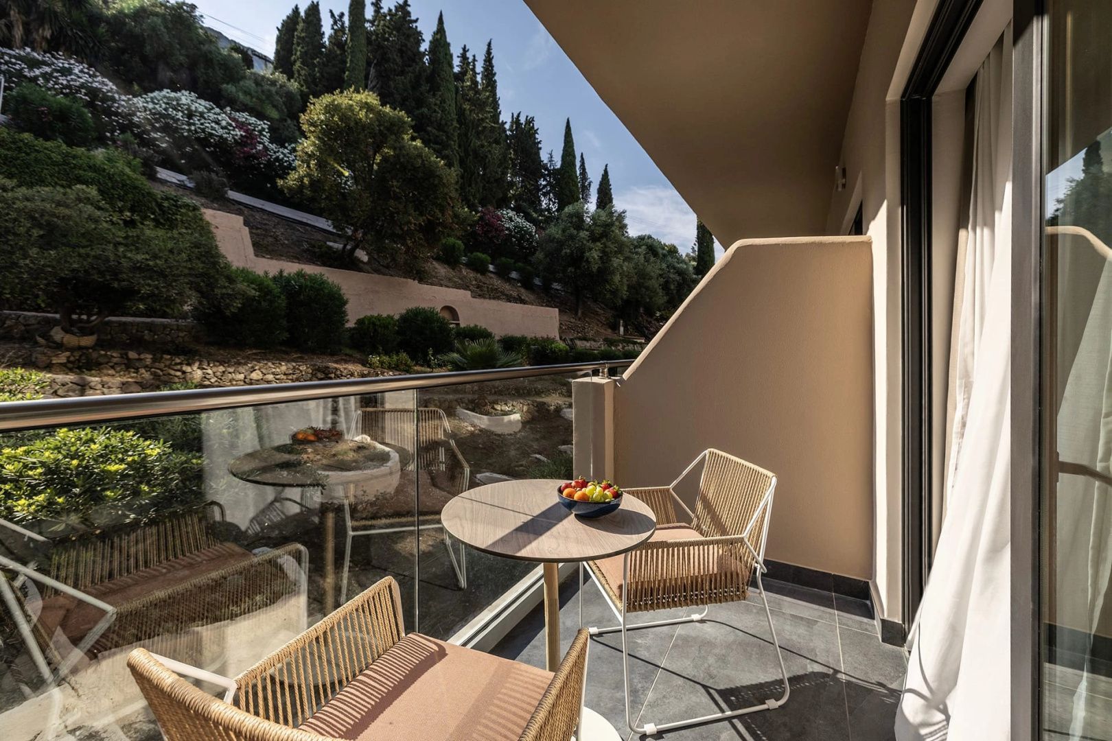 Balkon mit zwei Stühlen, kleinem Tisch und Blick auf die grüne Landschaft.