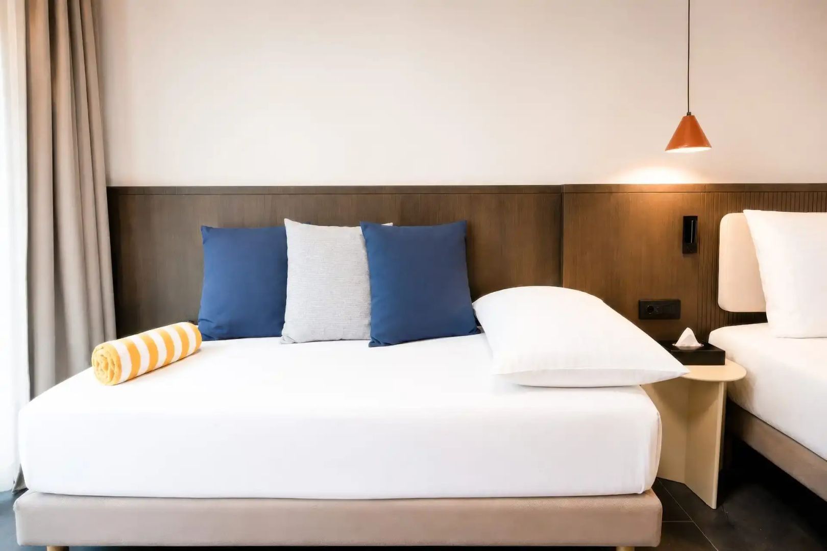 Tagesbett in einem Hotelzimmer mit blauen und grauen Kissen sowie Holzkopfteil.