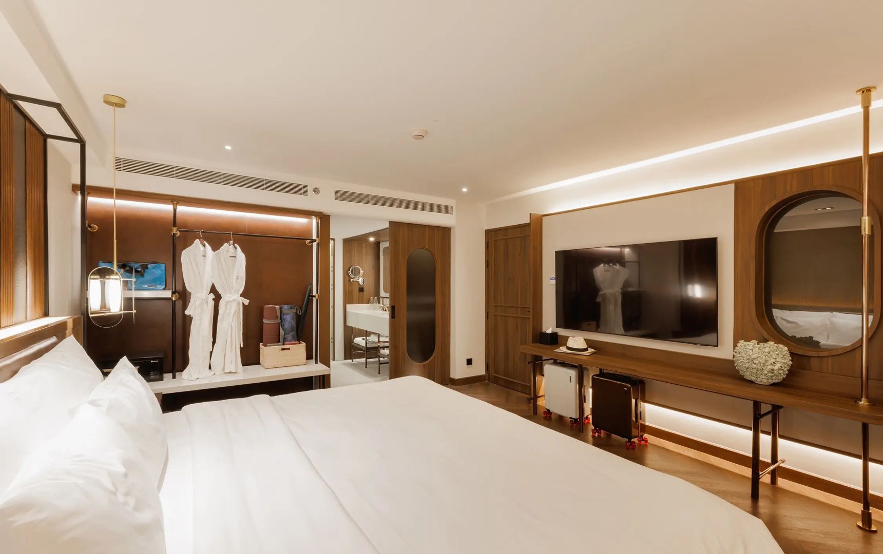 Hotelzimmer mit Fernseher an der Wand, Kofferablage und Blick ins angrenzende Badezimmer.