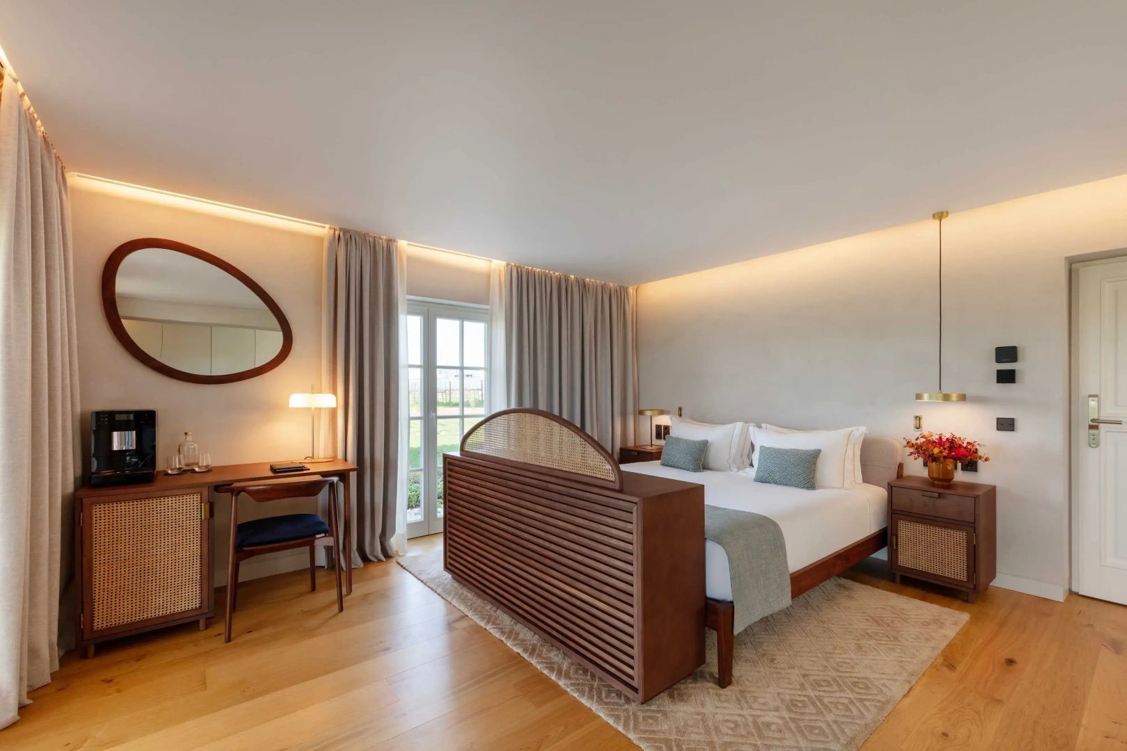 Hotelzimmer mit großem Doppelbett, Holzmöbeln und hellem Fußboden.