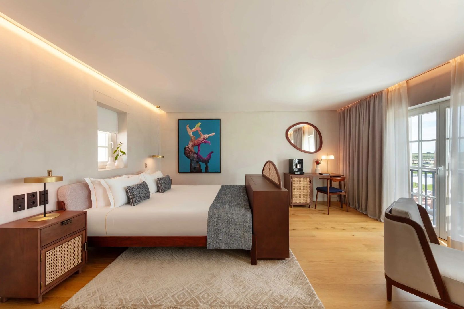 Hotelzimmer mit großem Doppelbett, hellem Holzboden und Kunstwerk an der weißen Wand.