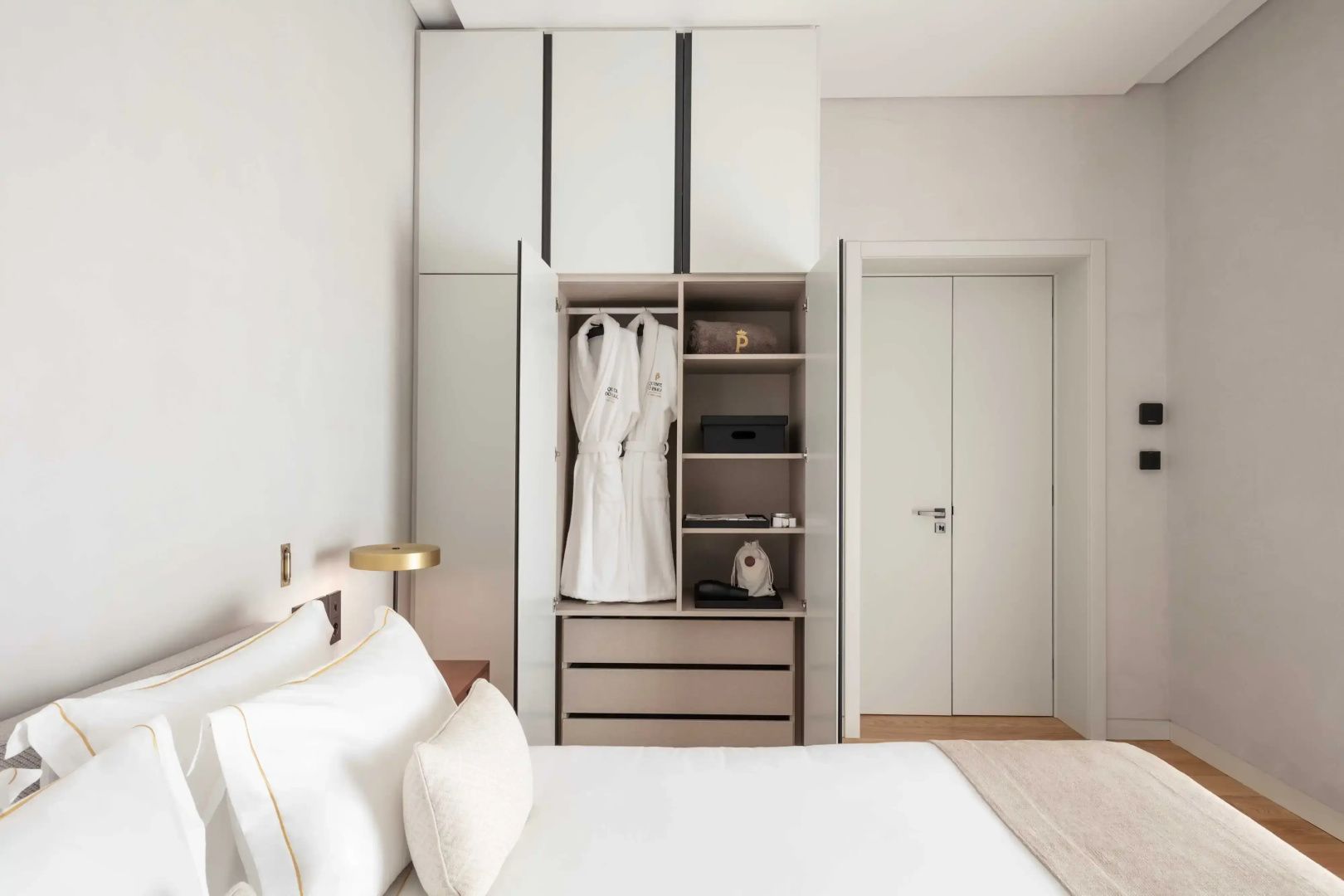 Geöffneter Einbauschrank im Zimmer mit zwei weißen Bademänteln auf Fächern.