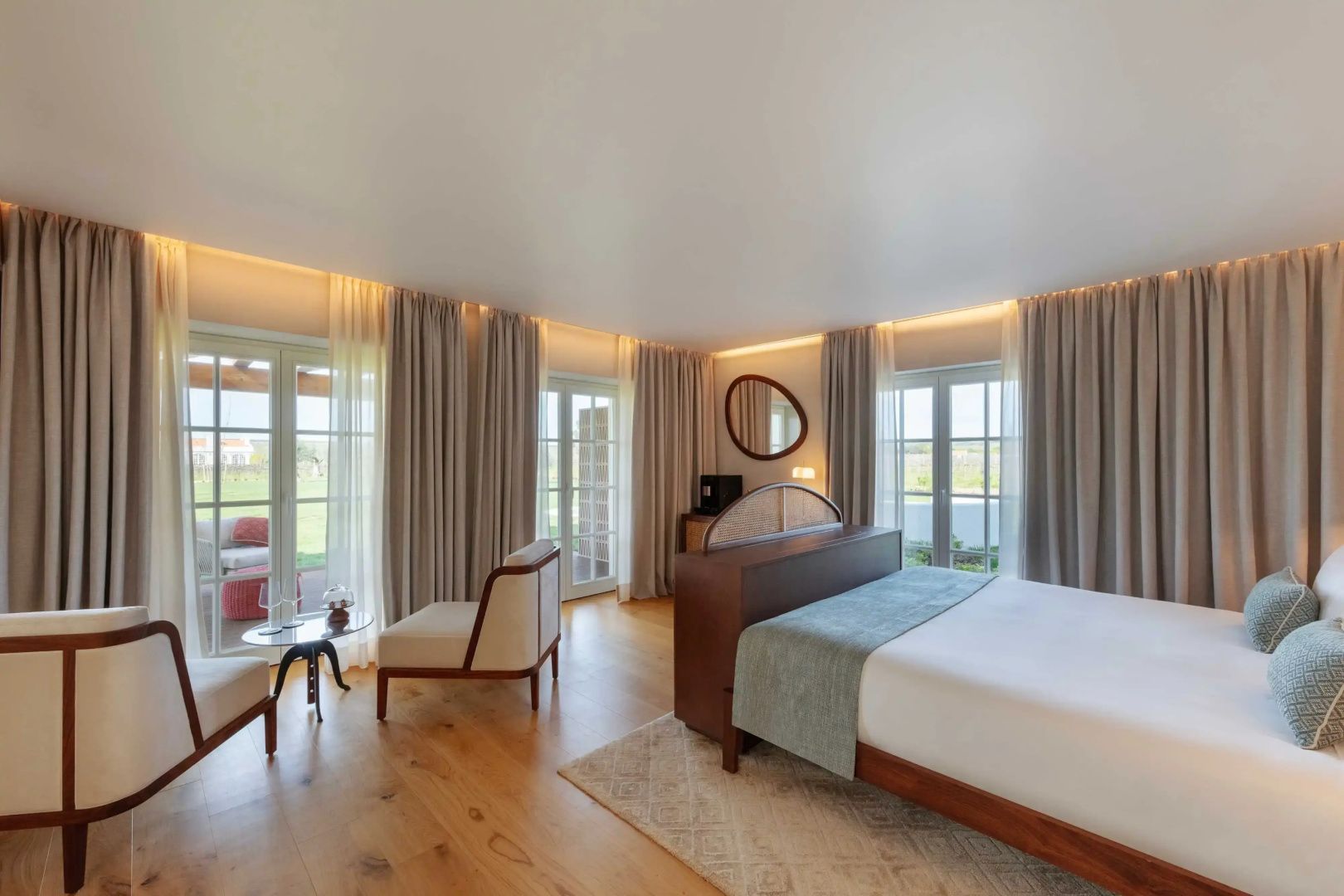 Helles Hotelzimmer mit großem Doppelbett, Sitzbereich und Zugang zum Außenbereich.