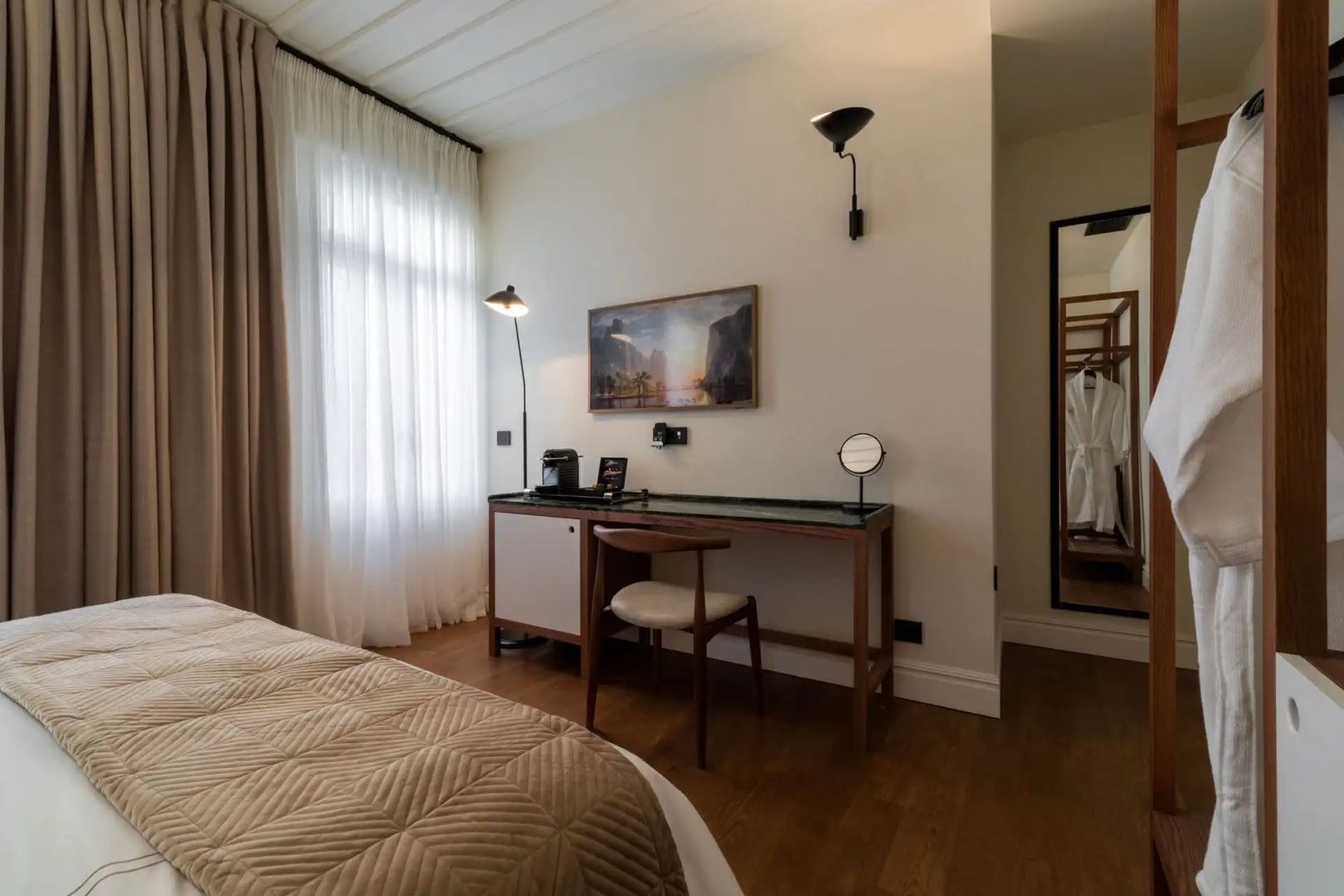 Ein Schreibtisch mit Stuhl und Spiegel in einem modern eingerichteten Hotelzimmer.