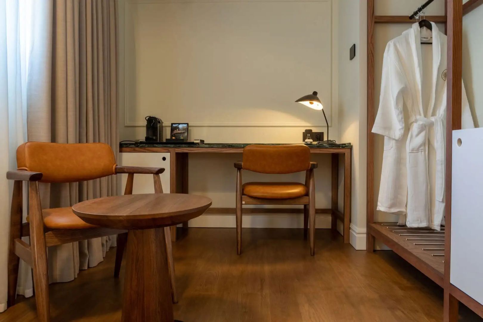 Schreibtisch mit Stuhl, Beistelltisch und Sessel aus Holz im modern eingerichteten Hotelzimmer.
