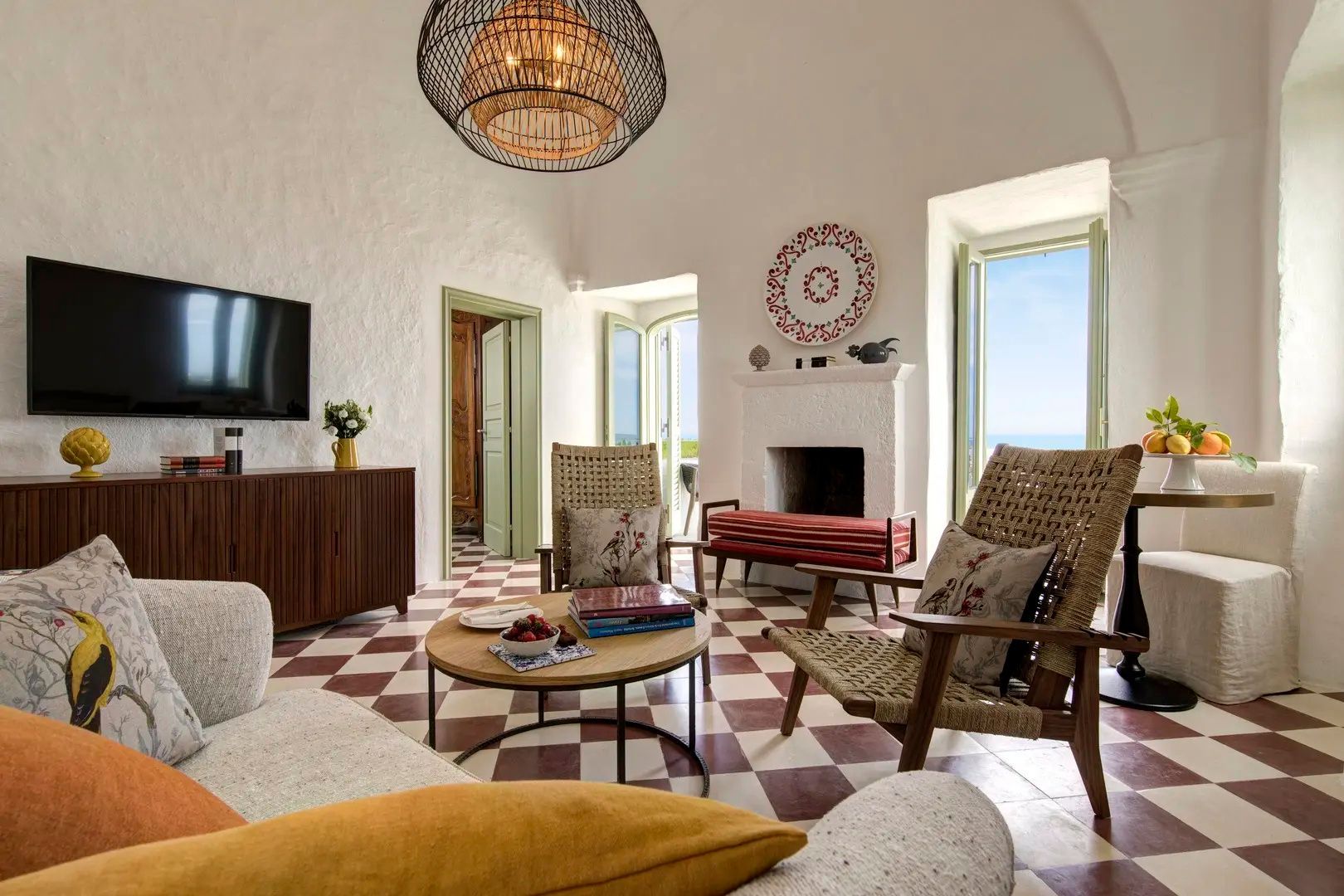 Wohnbereich einer Suite mit Flechtsesseln, Kamin, Couchtisch und Fliesenboden.