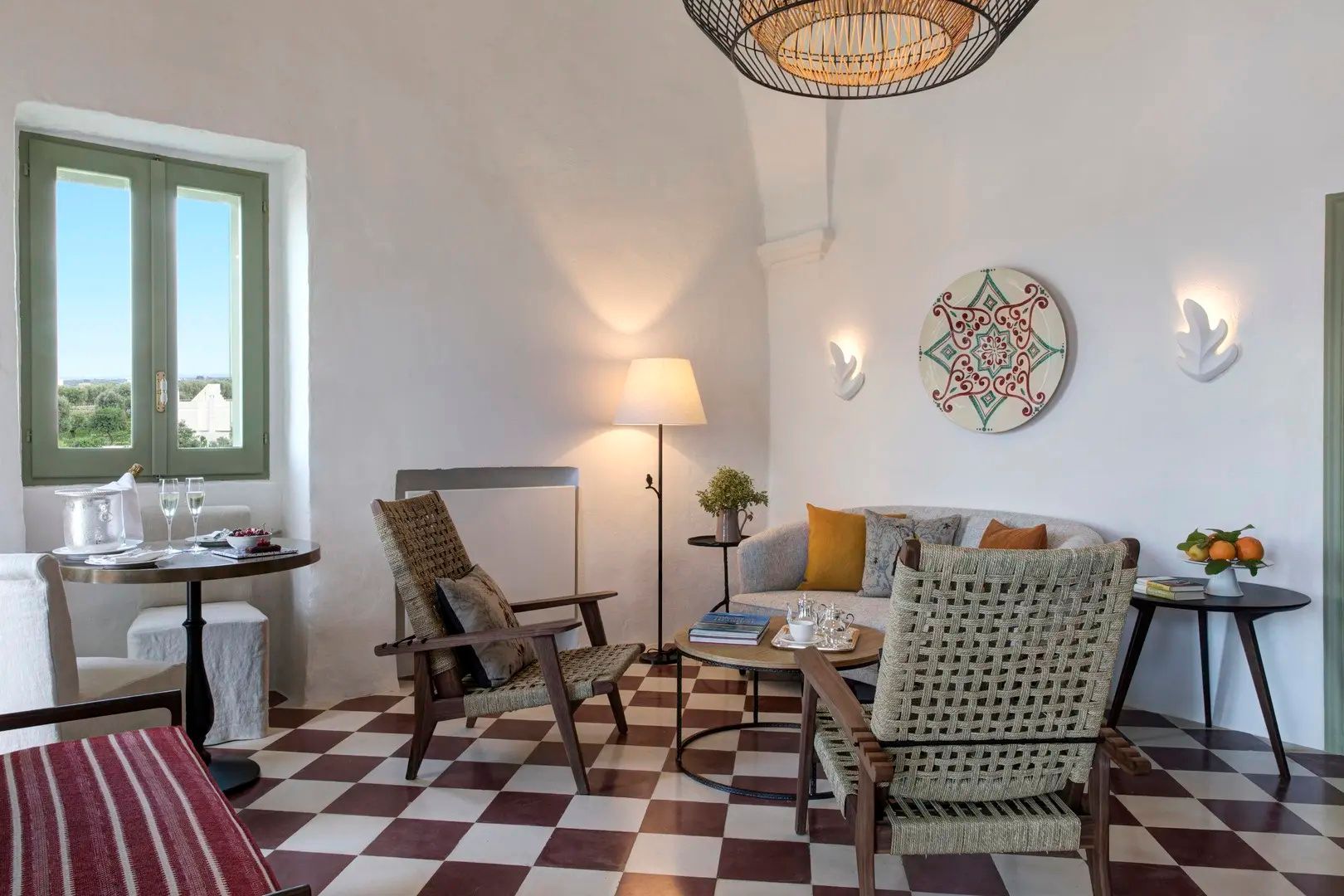 Sitzecke im Hotelzimmer mit Sofa, zwei Flechtsesseln, Stehlampe und Wanddekoration.