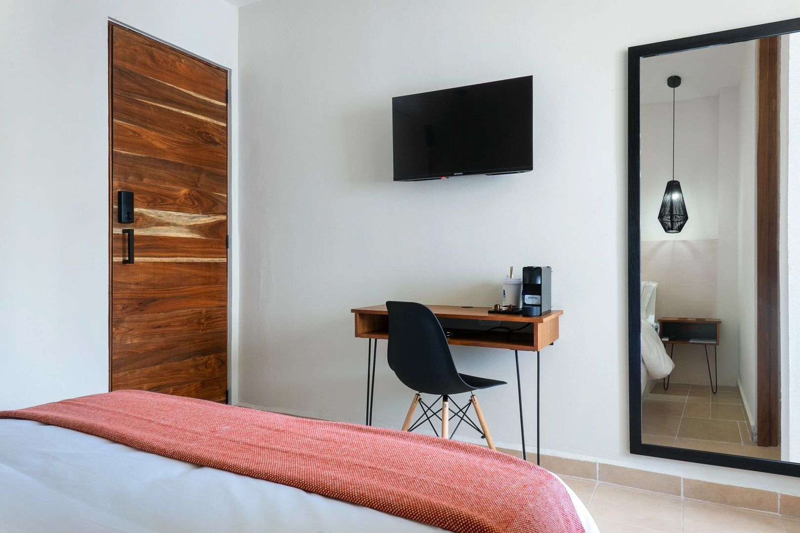 Schreibtisch mit Stuhl, Fernseher an der Wand und Holztür im Hotelzimmer.