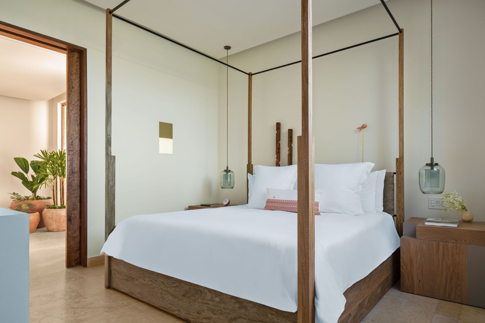Großes Himmelbett aus Holz mit weißer Bettwäsche in einem hell eingerichteten Schlafzimmer.