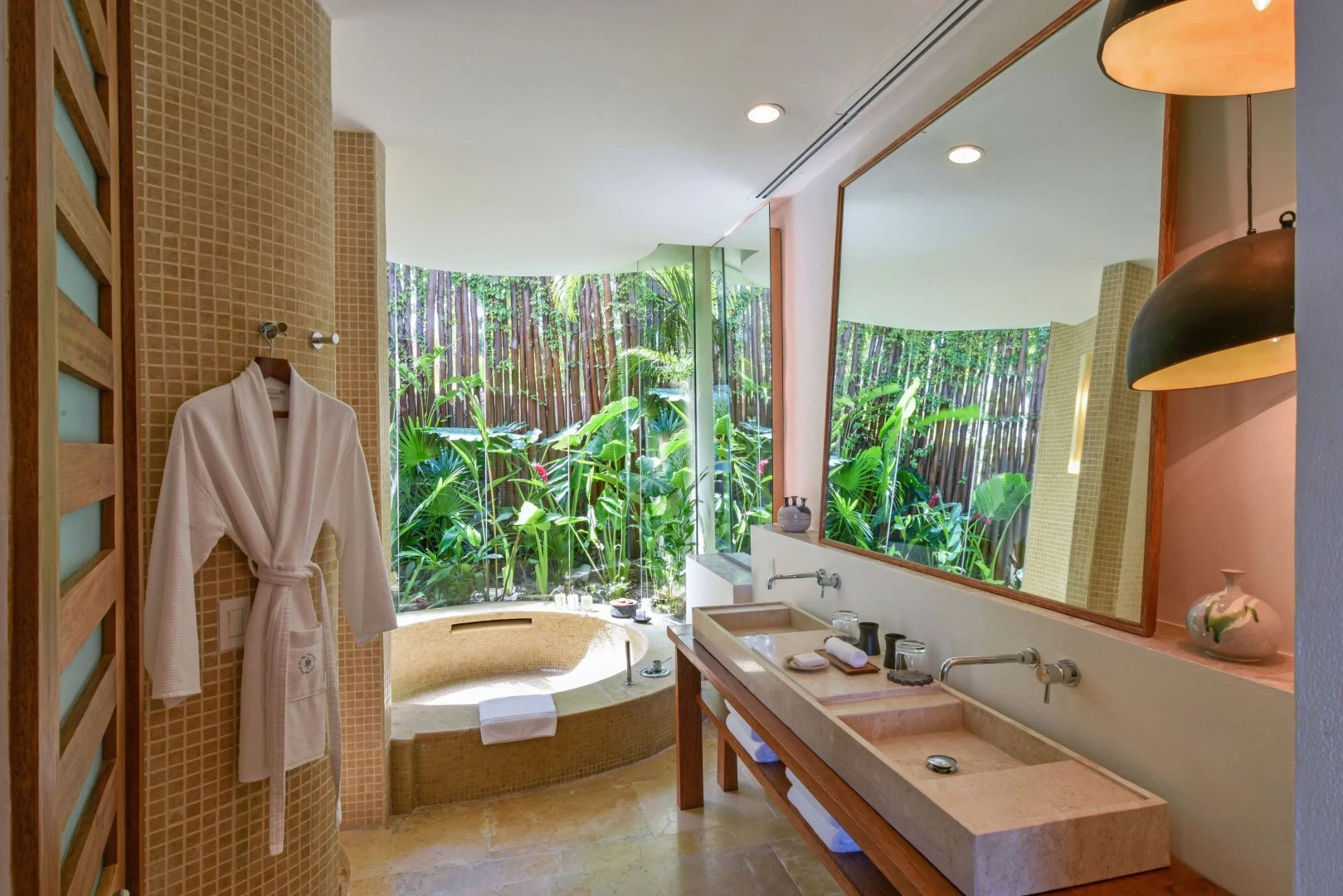 Badezimmer mit Doppelwaschtisch, großer Badewanne und Panoramafenster ins Grüne.