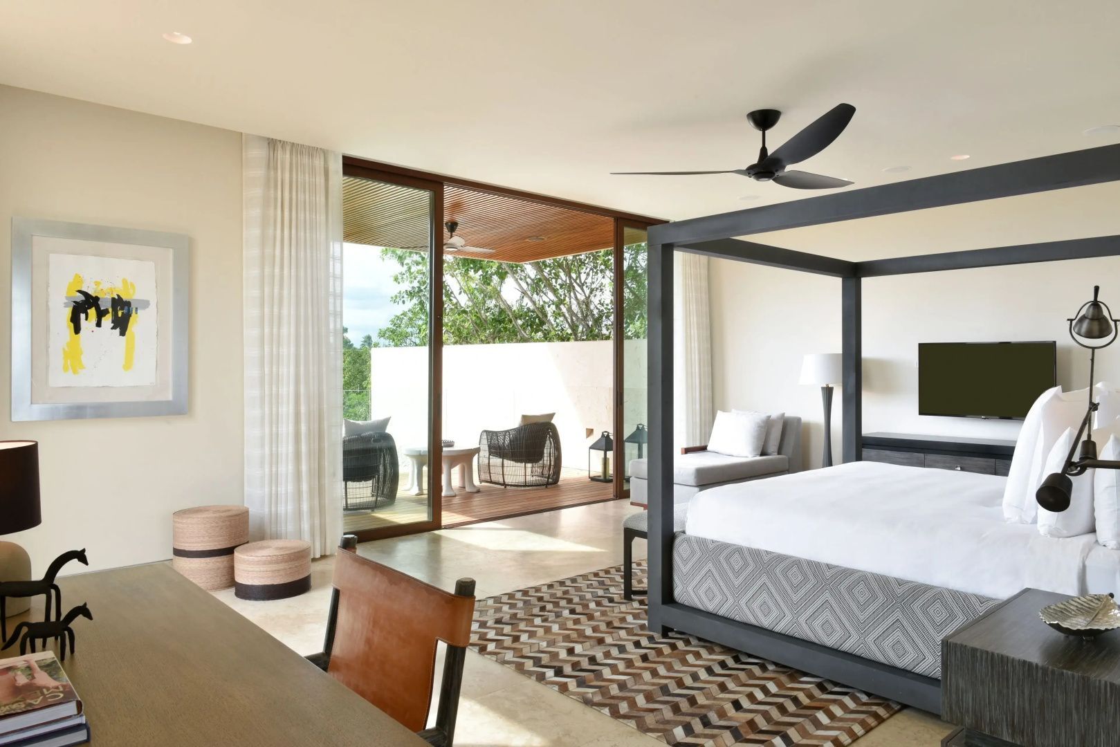 Hell eingerichtetes Schlafzimmer mit Himmelbett und Zugang zu einer überdachten Terrasse.