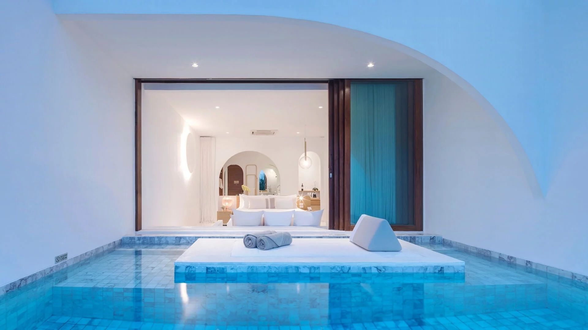 Außenansicht einer Suite bei Dämmerung mit Beleuchtung, offenem Zimmer und eigenem Pool.