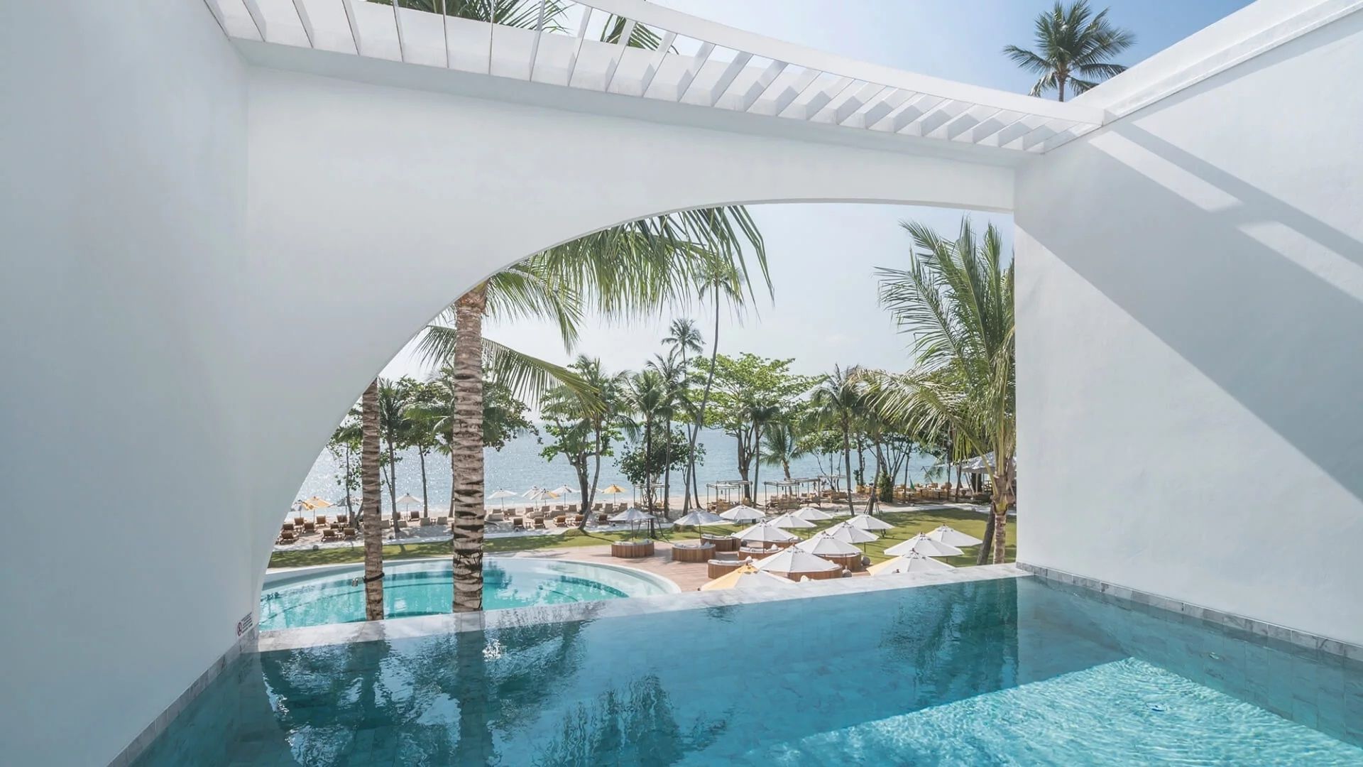 Blick vom privaten Pool auf den Garten, die Palmen und den angrenzenden Sandstrand.