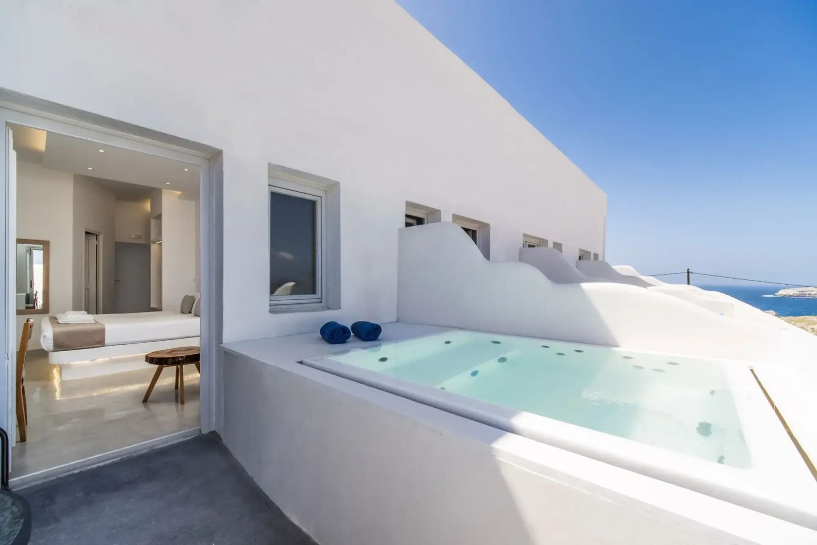 Weiße Außenfassade mit eingelassenem Whirlpool auf der Terrasse und blauem Handtuch.