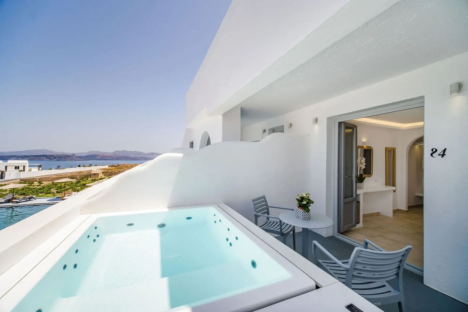 Weiße Terrasse mit integriertem Whirlpool, Sitzgruppe und Blick auf das Meer.