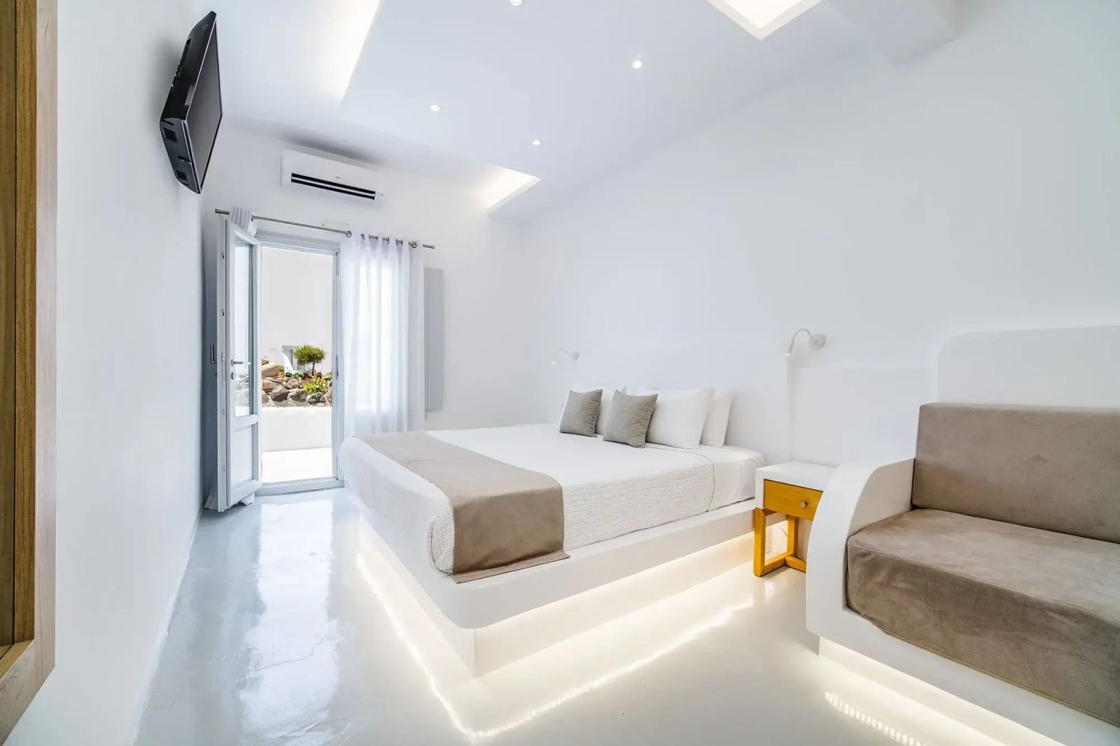 Weißes Schlafzimmer mit beleuchtetem Bettgestell und Sitzbereich.