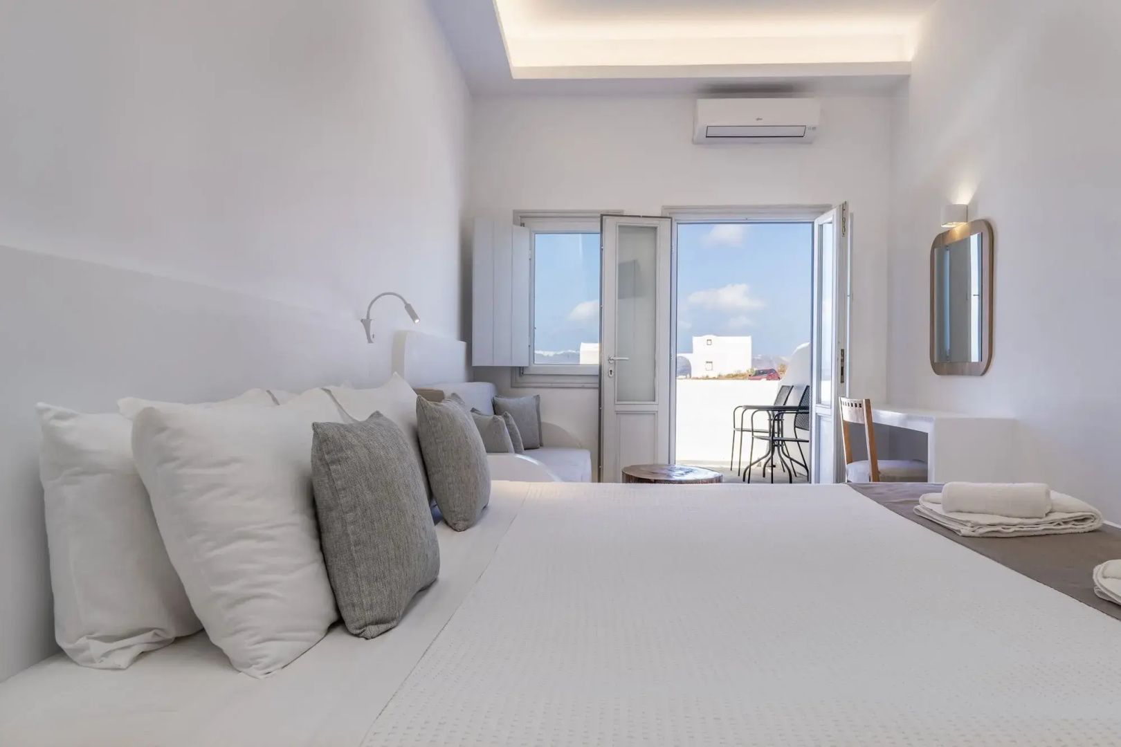 Helles Hotelzimmer mit Doppelbett, weißen Wänden und Blick durch die Balkontür.