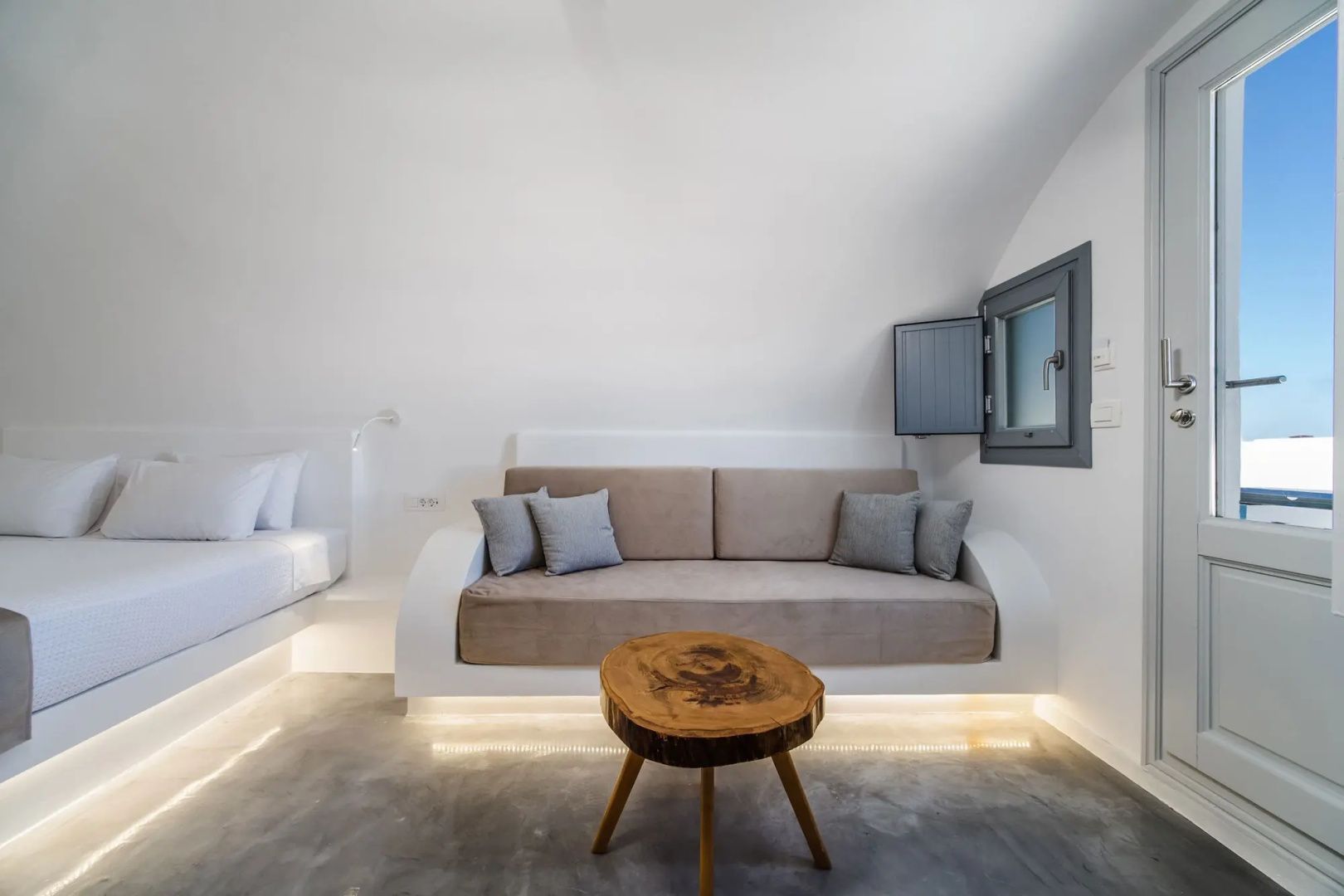 Sitzbereich im Zimmer mit beige Polstercouch und rundem Beistelltisch aus Holz.