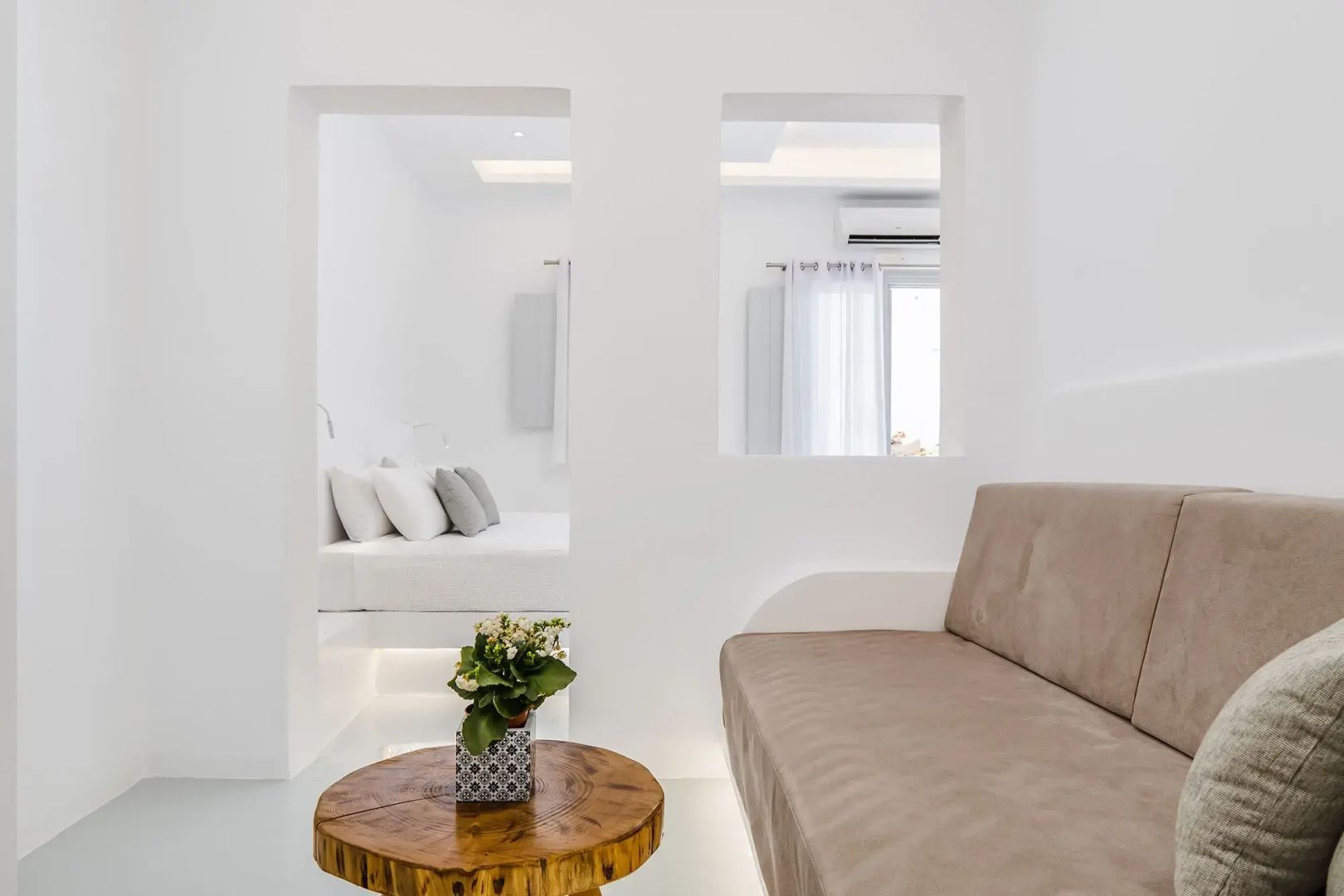 Wohnbereich mit braunem Sofa und Holztisch sowie Blick ins Schlafzimmer.