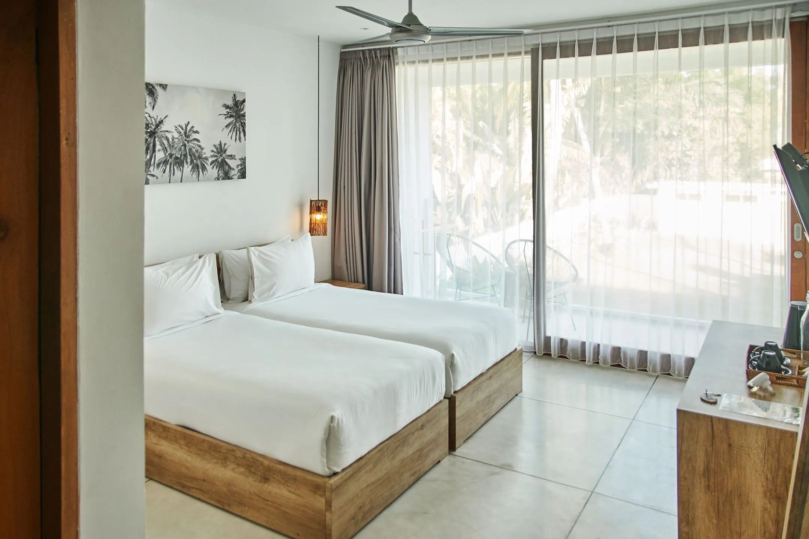 Hell eingerichtetes Hotelzimmer mit zwei Einzelbetten und großer Glasschiebetür.