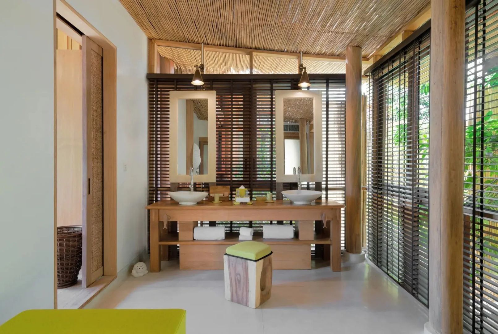Badezimmer mit doppeltem Waschtisch aus Holz, zwei Spiegeln und Jalousien.