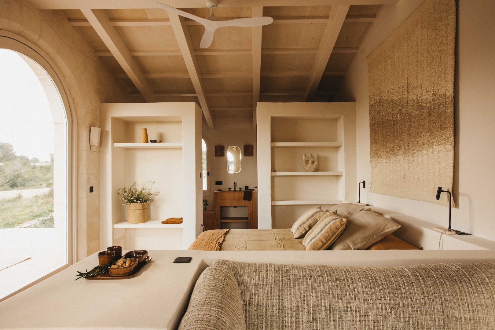 Schlafbereich einer Suite mit Holzdecke, Doppelbett und gemauerten Regalen.