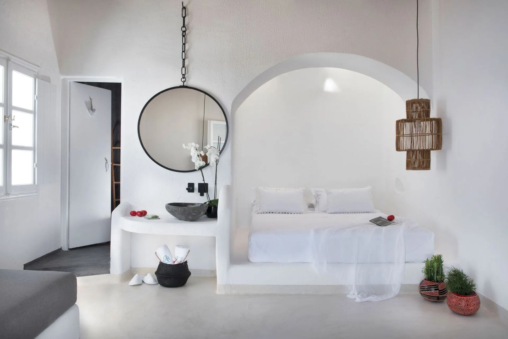 Weiß eingerichtetes Zimmer mit Doppelbett in einer Nische und Waschtisch.