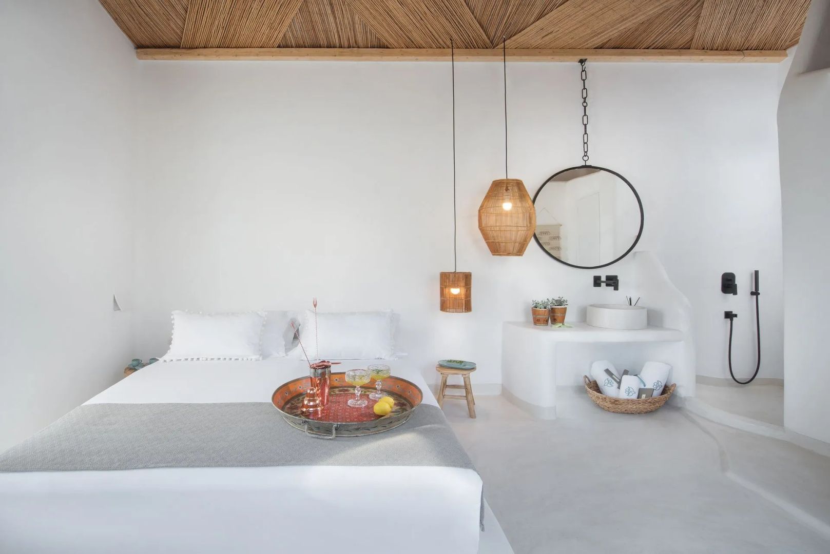 Hell gestaltetes Schlafzimmer mit weißem Bett, Holzdecke und hängenden Flechtlampen.