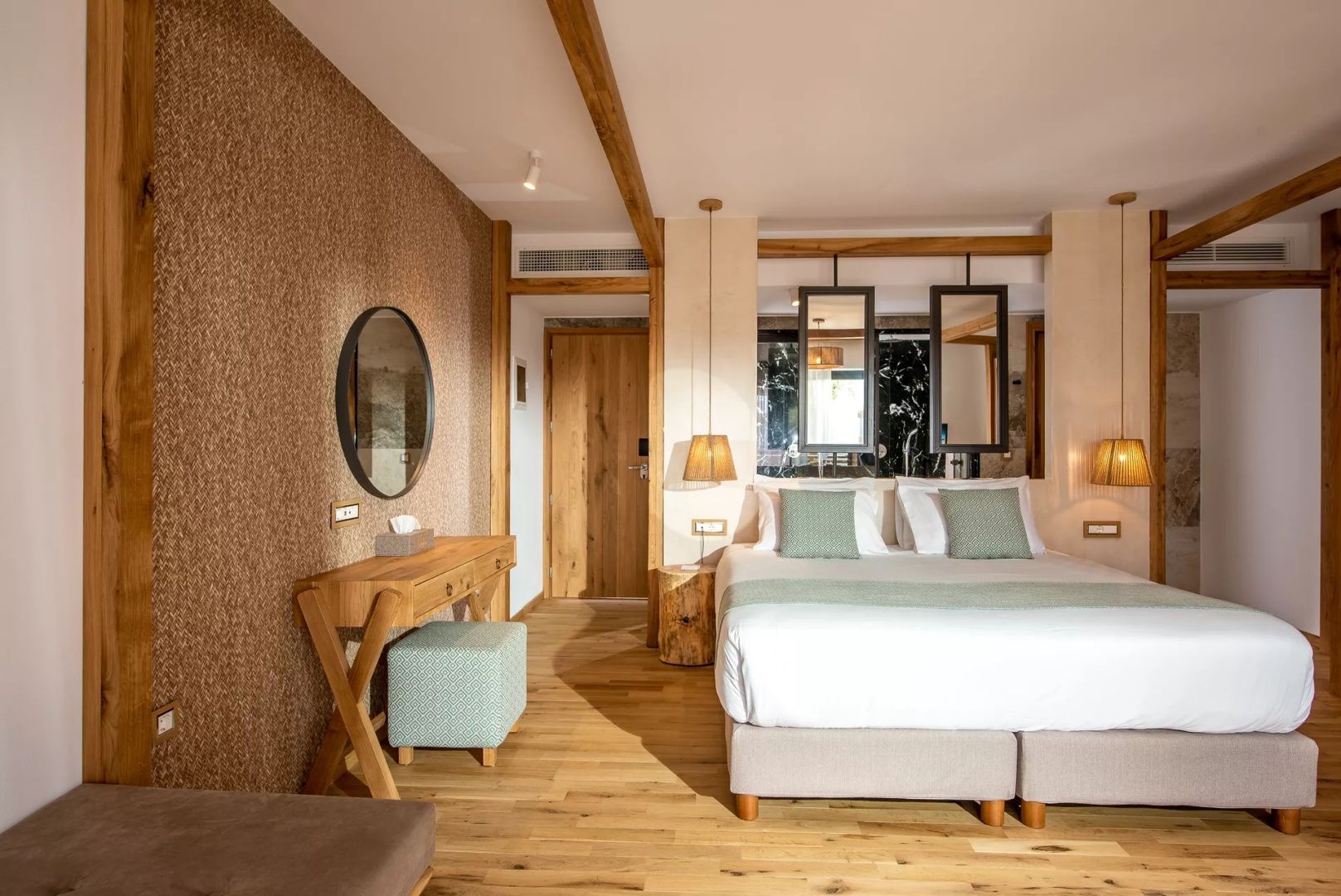 Helles Hotelzimmer mit Doppelbett, Holzboden und Schminktisch aus Holz.