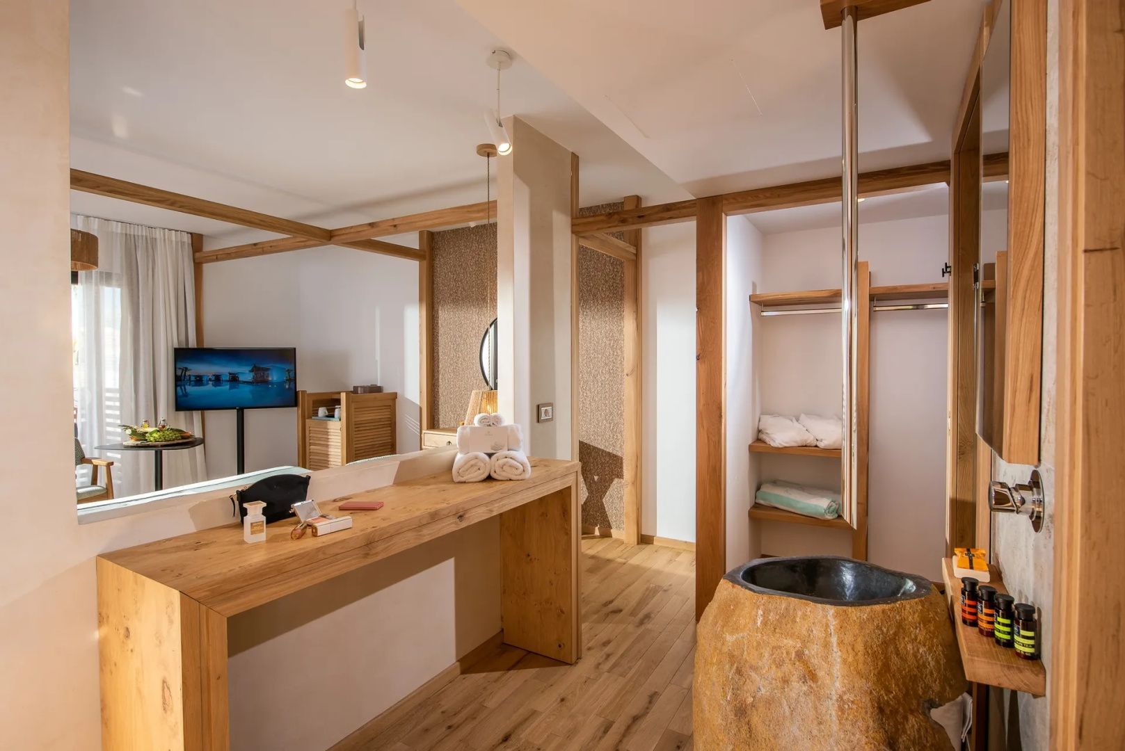 Waschbereich der Suite mit einem Waschbecken aus Naturstein und Holzmöbeln.