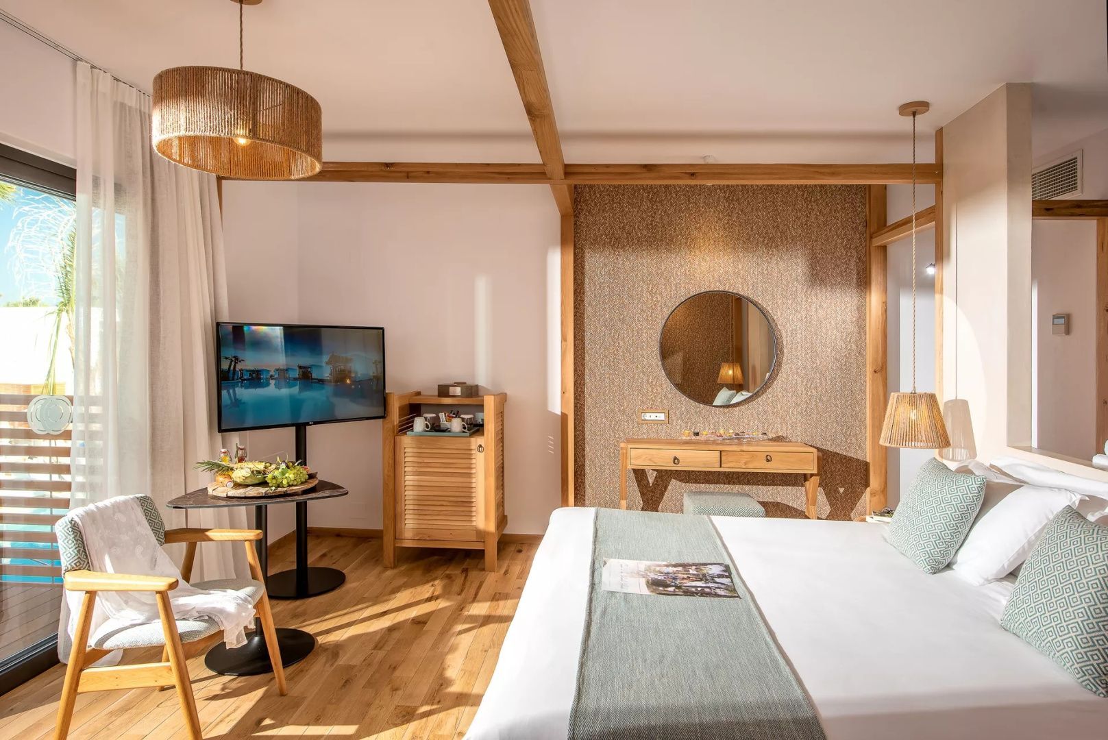 Helles Schlafzimmer im Hotel mit großem Doppelbett, Fernseher und Holztisch.