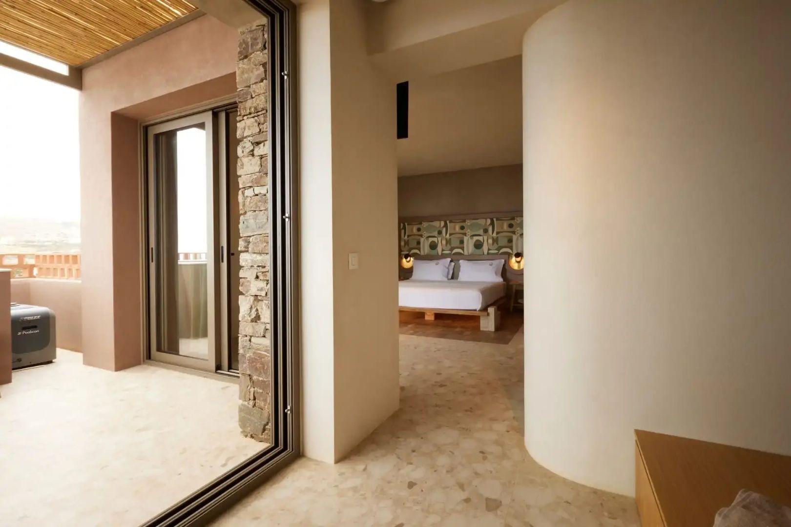 Blick in ein Hotelzimmer mit Doppelbett und angrenzendem Balkonzugang.