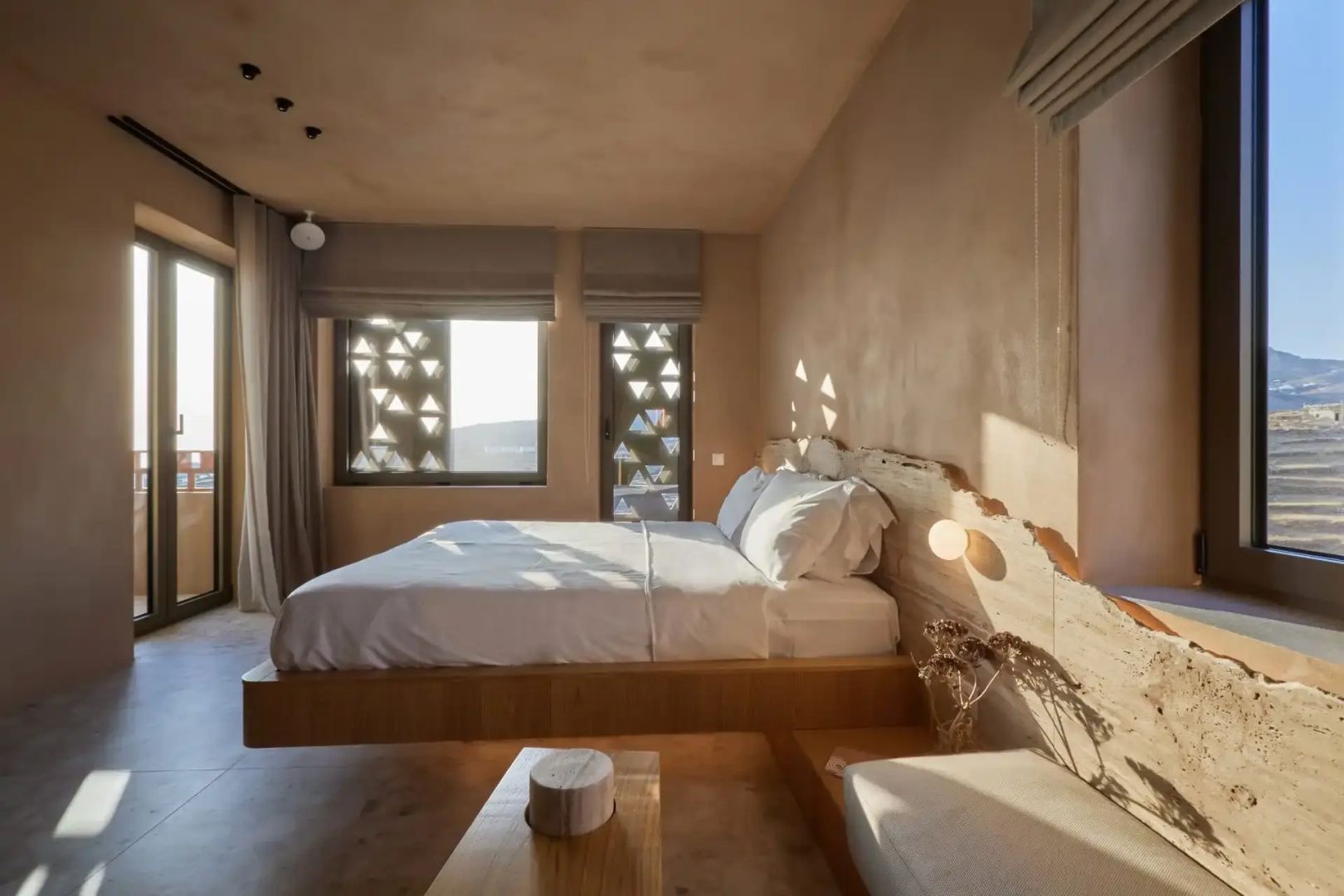 Schlafzimmer mit einem Holzdoppelbett, hellen Wänden und schattierenden Fensterläden.