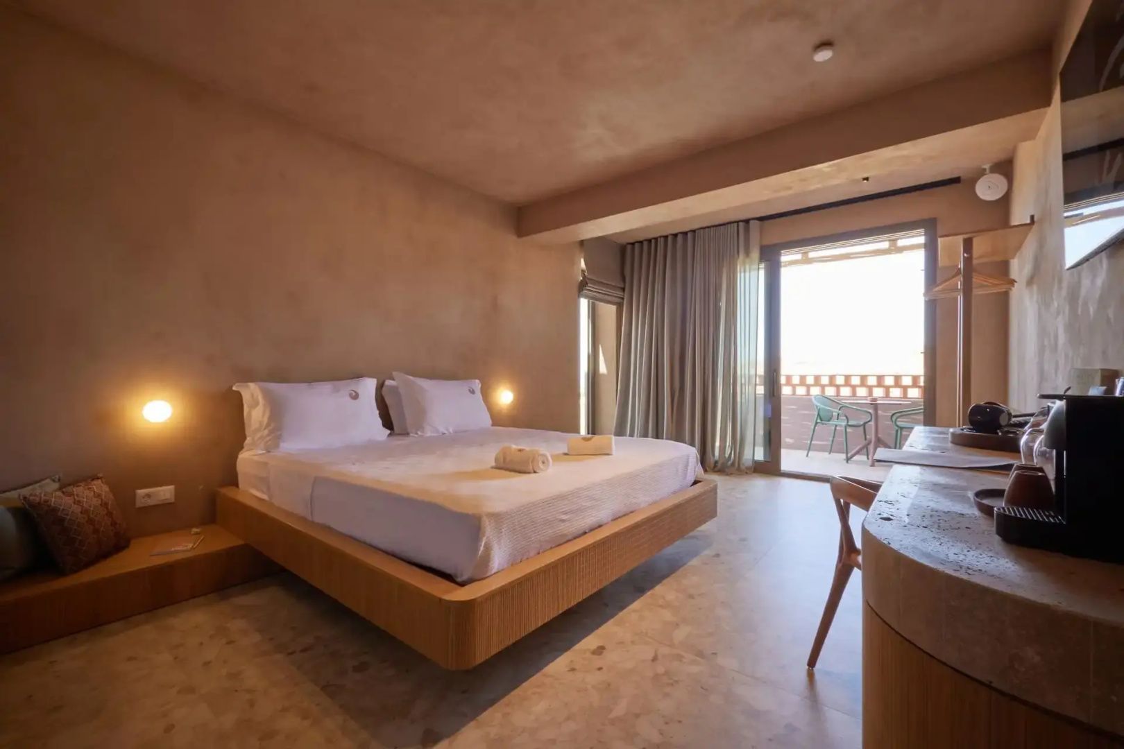 Großzügiges Schlafzimmer mit Holzdoppelbett, Schreibtisch und Zugang zur eigenen Terrasse.