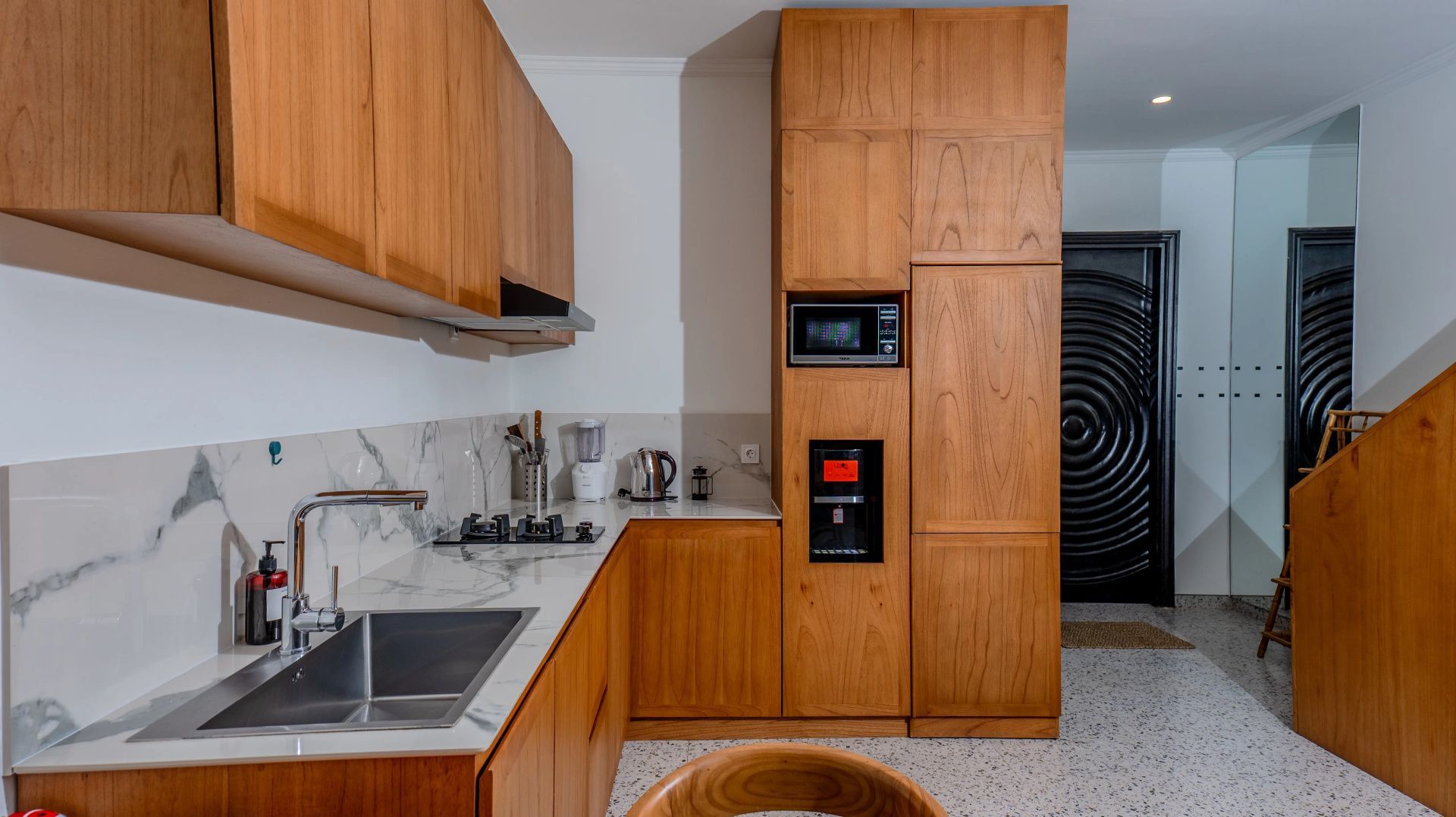 Moderne Küche mit Holzschränken, Marmorarbeitsplatte, Spülbecken und Kochfeld.