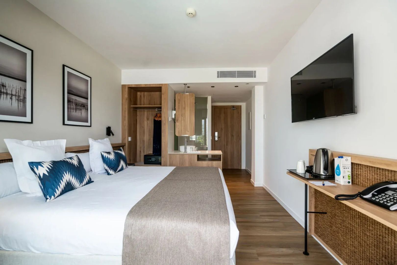 Blick in das Hotelzimmer mit großem Bett und einem Fernseher an der Wand.