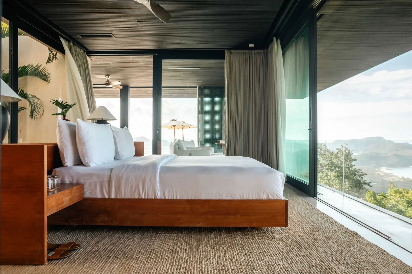 Schlafzimmer mit geöffneten Glasfenstern und weitem Blick auf die Landschaft.