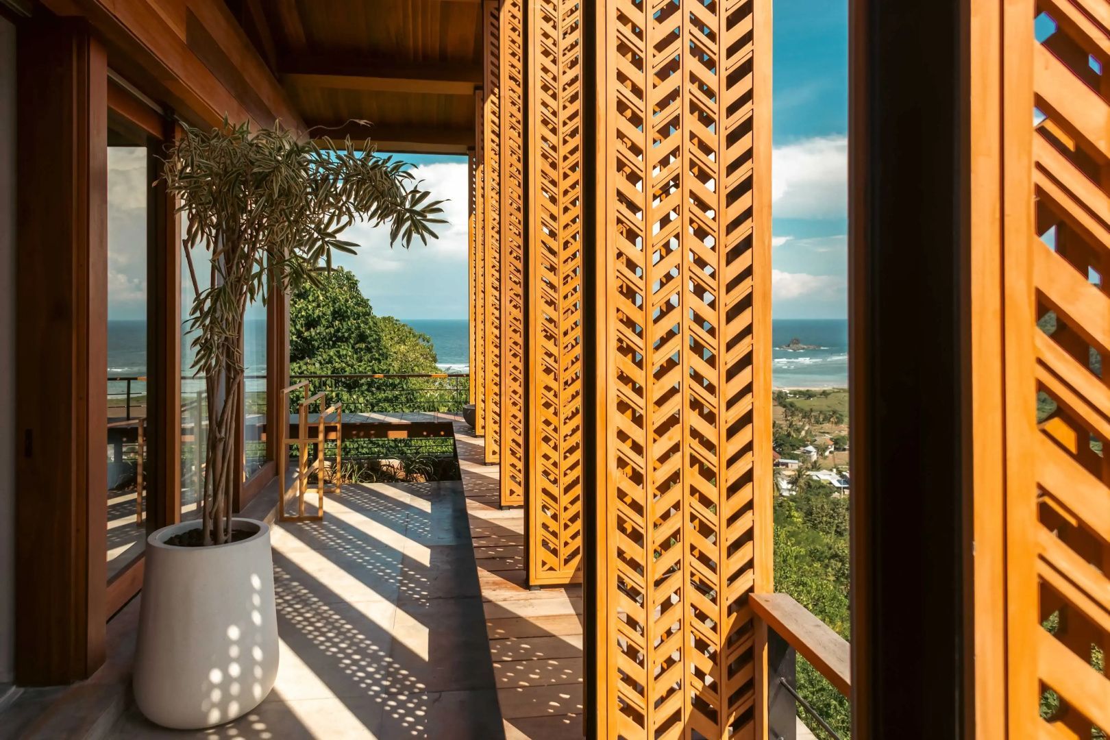 Überdachter Balkon mit verzierten Holzpaneelen und Aussicht auf die Küstenlandschaft.
