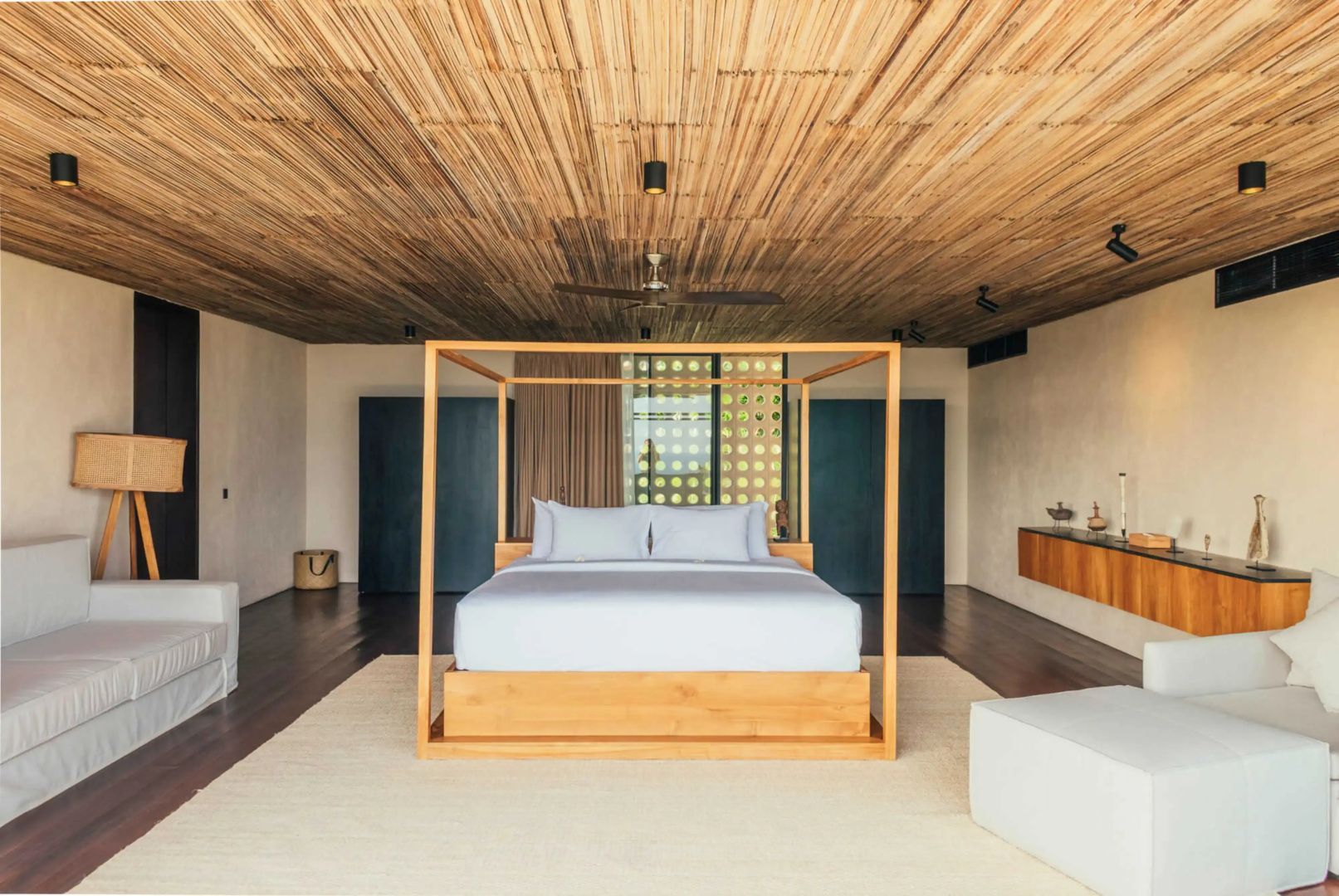 Schlafzimmer mit einem großen Holzhimmelbett und einer Decke aus Bambusleisten.