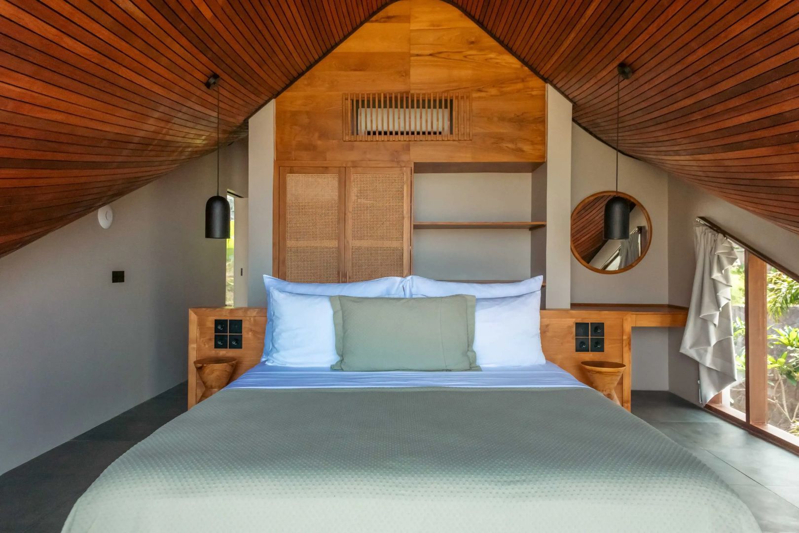 Schlafzimmer unter einer Holzschräge mit eingebauten Schränken und Nachttischen.