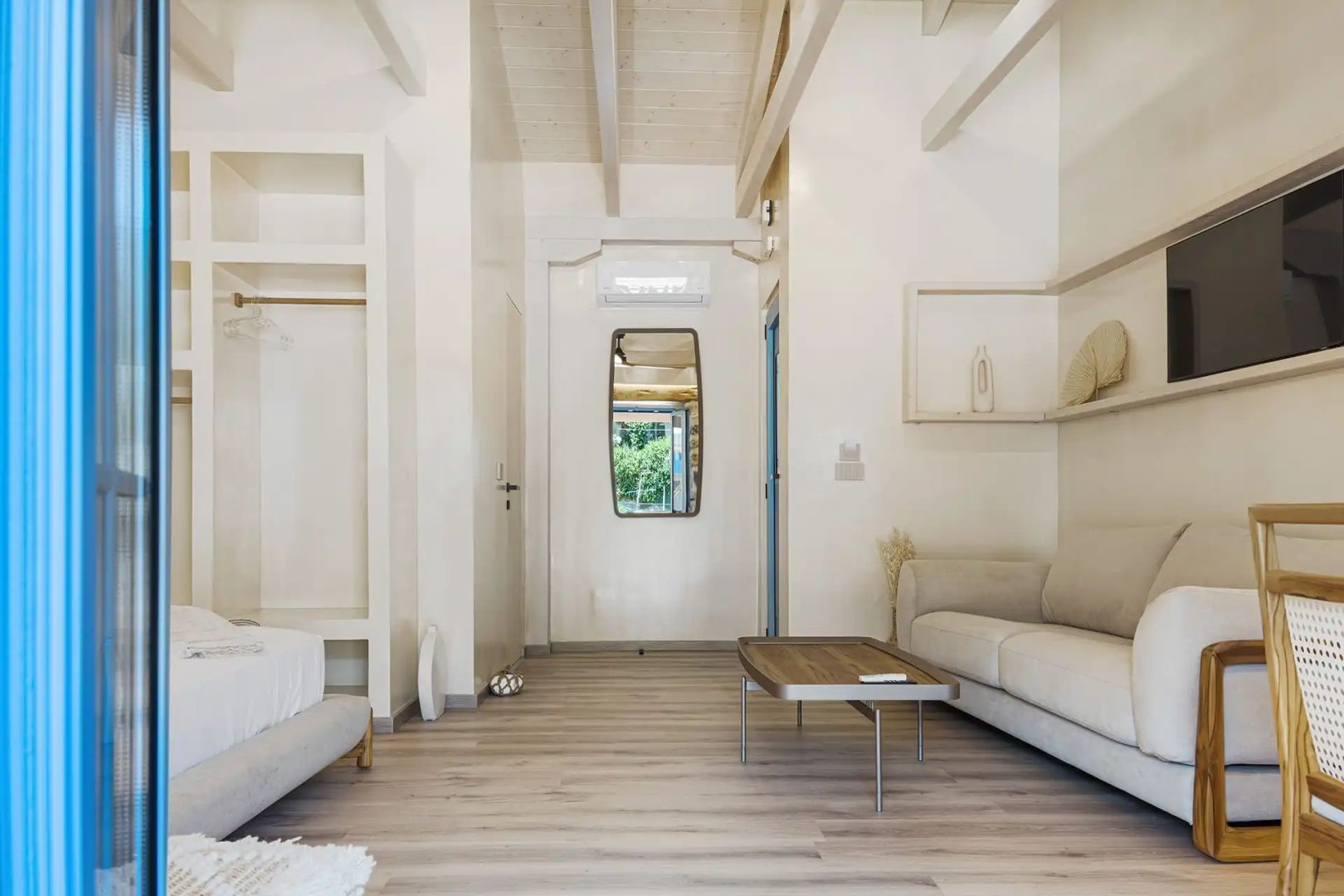 Heller Raum einer Suite mit weißem Sofa, flachem Couchtisch und spitz zulaufender Decke.