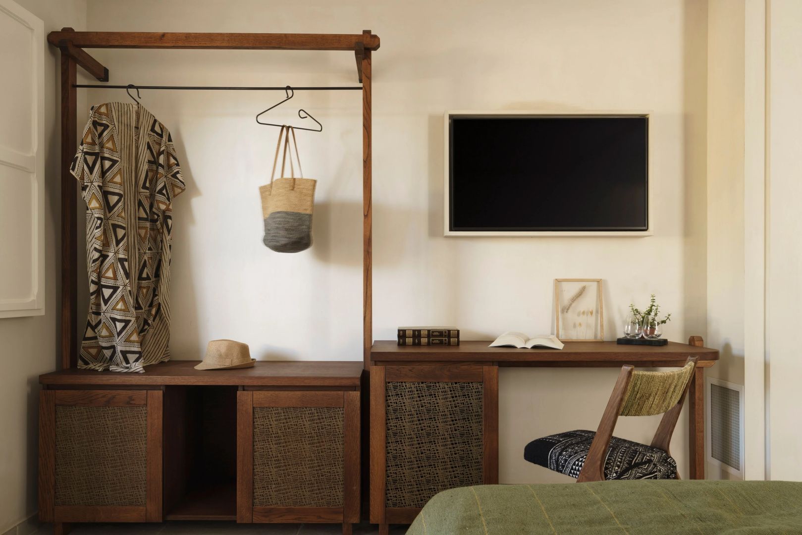 Holzgarderobe und Schreibtisch mit Fernseher an der Wand in einem hell eingerichteten Zimmer