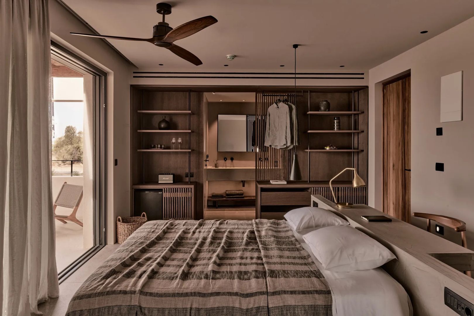 Doppelbett in einer Suite mit Deckenventilator und offenem Holzkleiderschrank.