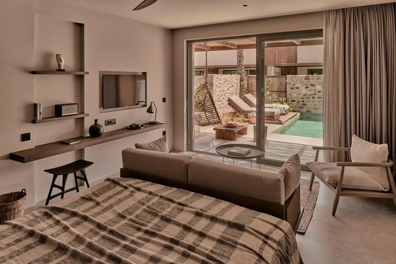 Blick aus der Suite durch eine Glasschiebetür auf die Terrasse mit privatem Pool und Liegestühlen.