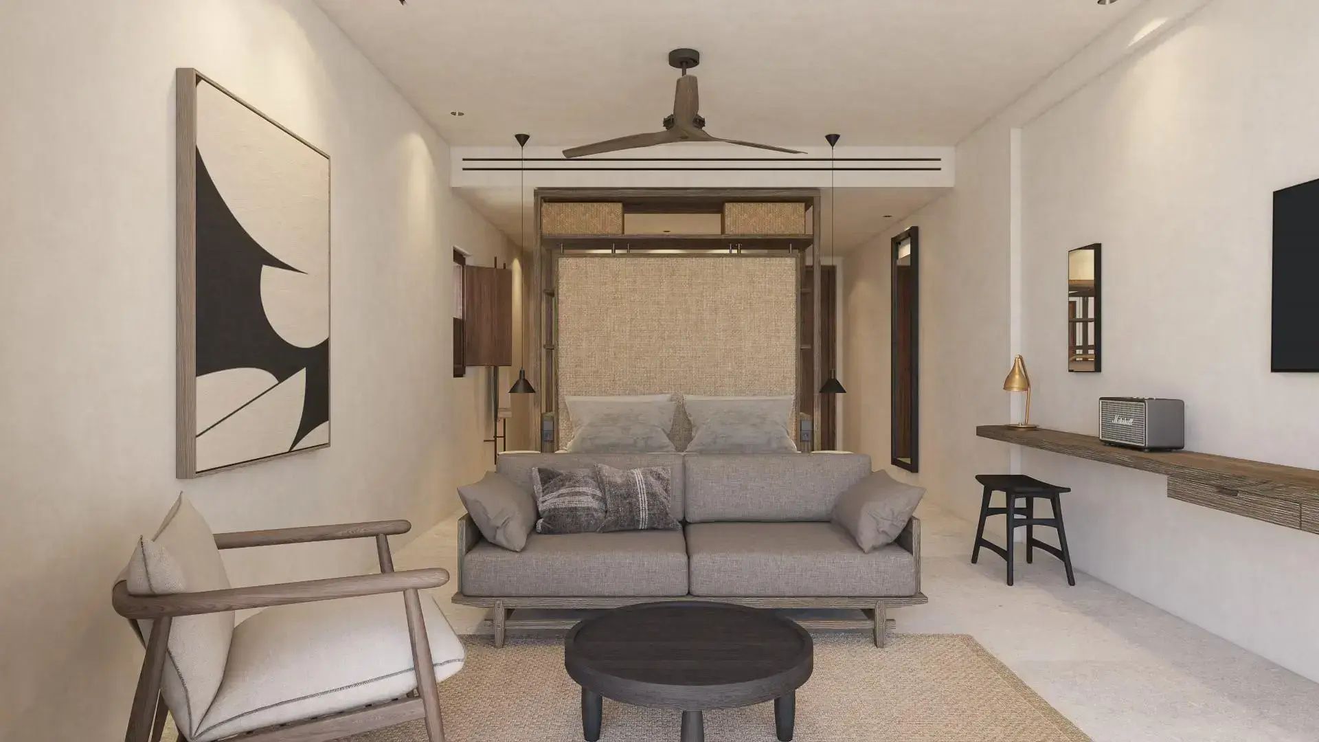 Helles Zimmer mit grauem Sofa, rundem Couchtisch und Bett im Hintergrund.