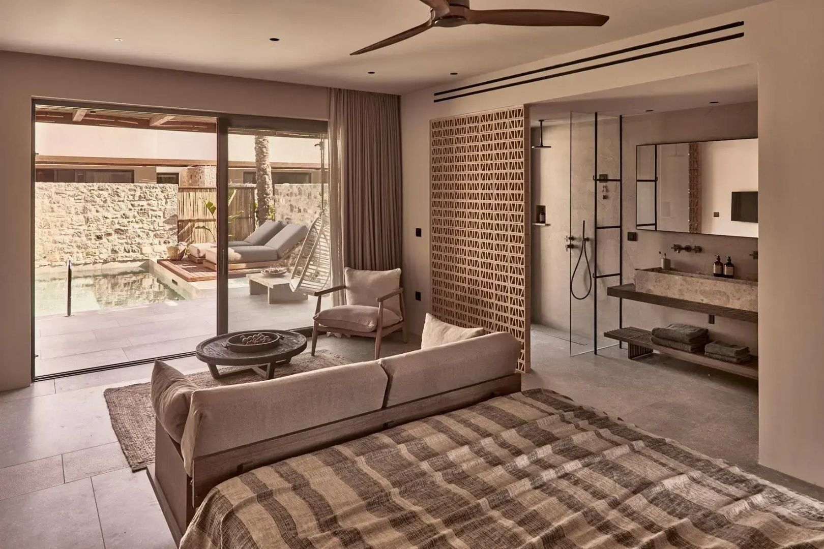 Einrichtungsbeispiel einer Suite mit Sitzbereich und Übergang zur Terrasse mit Pool.