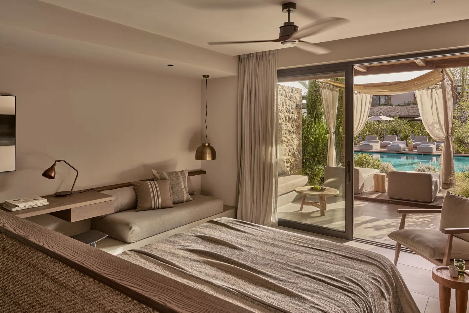 Blick aus dem Zimmer durch eine geöffnete Glasfront auf die Terrasse und den Pool.