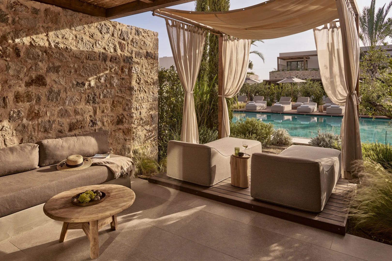 Überdachte Terrasse mit Sitzgelegenheiten und Blick auf den Außenpool.