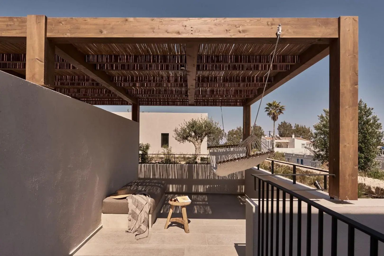Überdachte Terrasse mit Holzpergola, Liegebett, Hängematte und Sitzgelegenheit.