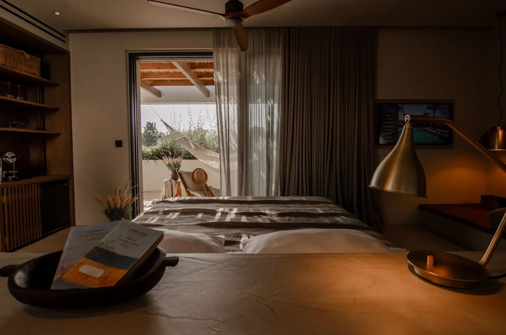 Blick vom Bett auf den angrenzenden Balkon mit einer Hängematte im Freien.